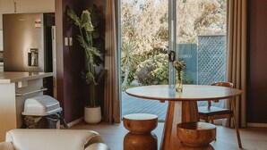 Une cuisine moderne dotée d’un réfrigérateur encastré, d’un coin repas avec une table et des tabourets en bois, et d’une plante en pot.