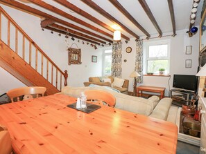 Relax in this inviting living space with a dining table, comfortable seating, and a staircase leading to an upper level.