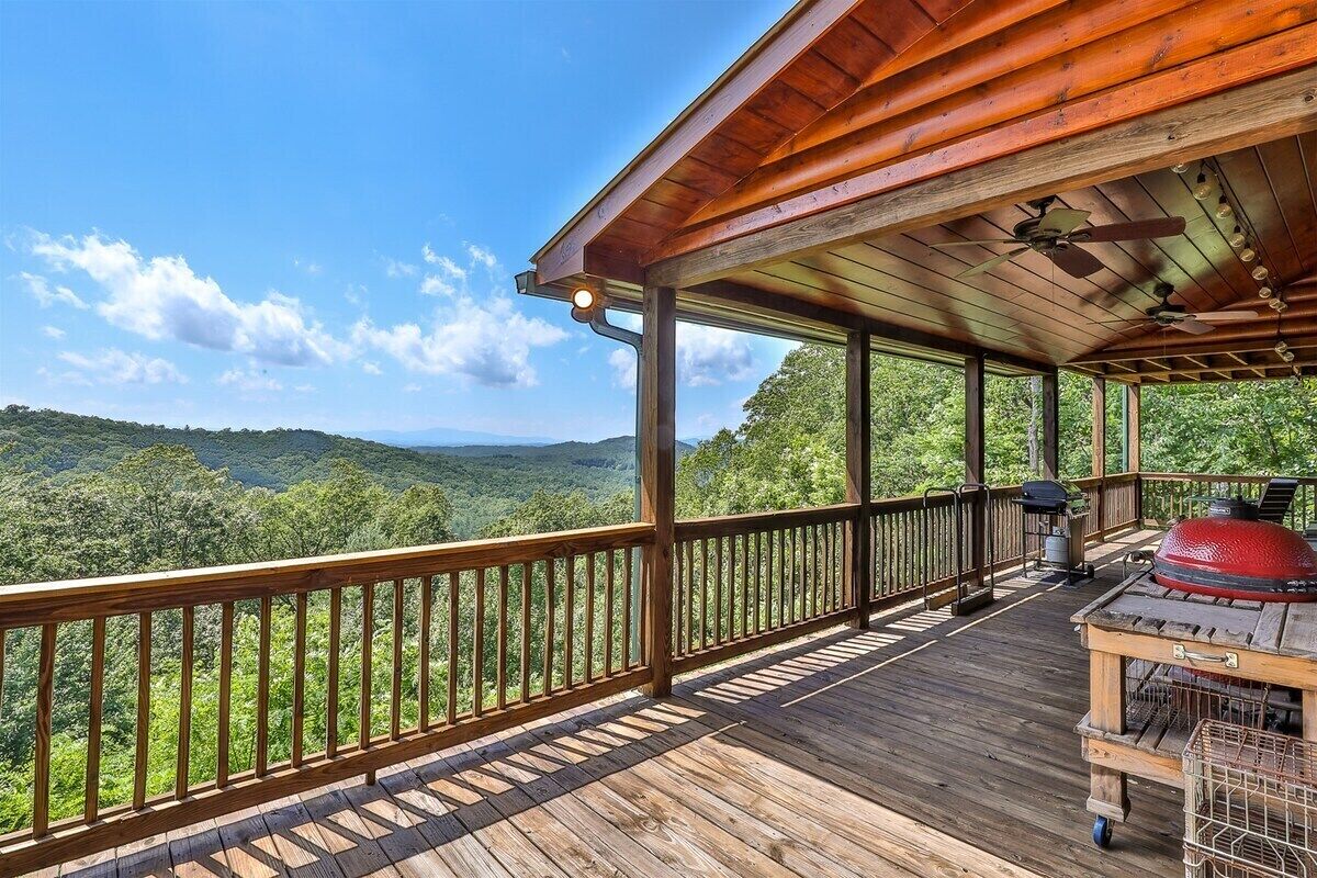 Une terrasse en bois dotée d’une rambarde, qui offre une vue sur un paysage boisé.