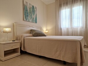 A bedroom with a bed, nightstand, lamp, and artwork on the wall. - A88 EDIFICIO LARIMAR 8-D (Calpe)