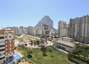 A residential area with high-rise buildings, a central plaza with palm trees, and a large rock formation in the background. - A88 EDIFICIO LARIMAR 8-D (Calpe)