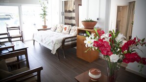 Un dormitorio con cama, cómoda de madera, mesa de comedor con sillas y una planta en maceta.