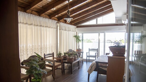 Una habitación acogedora con vigas de madera, una mesa de comedor con sillas y plantas en macetas.