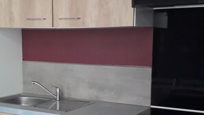 Ett modernt kök med träskåp, en diskho i rostfritt stål, en svart spis och ett vitt matbord.