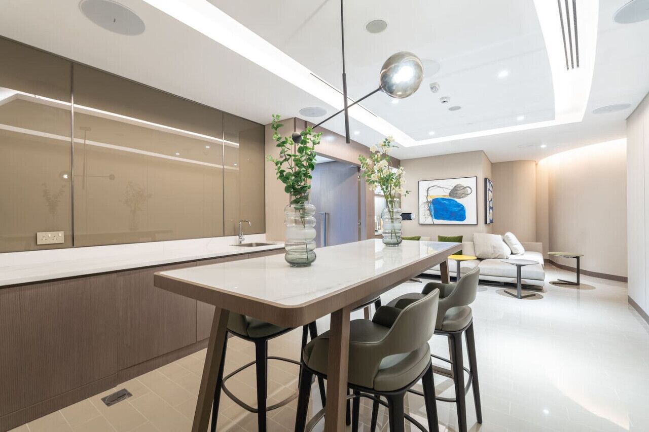 Une cuisine moderne dotée d’un îlot central, de tabourets de bar et d’un coin repas comprenant un canapé et une table basse.