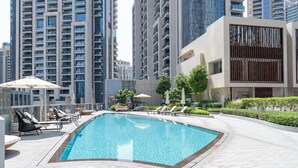 A rooftop swimming pool with lounge chairs and umbrellas, surrounded by modern buildings. - Vogue, Downtown Opera Grand near Burj Khalifa & Dubai Mall, with Fountain view (Dubai)