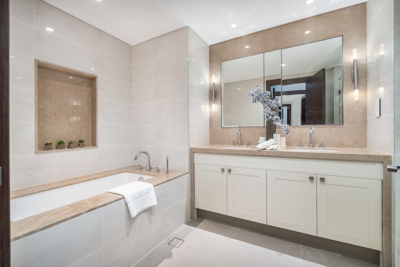 Un baño moderno con una bañera grande, un tocador con espejo y un estante con pequeñas plantas.