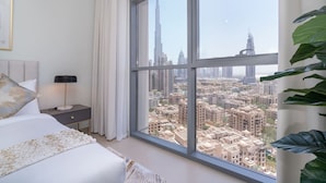 Camera da letto con un'ampia finestra che offre vista su un panorama urbano, con un grattacielo ben visibile.
