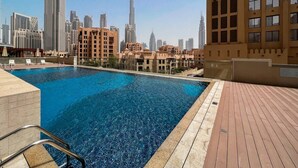 Una piscina sul tetto con lo skyline della città sullo sfondo, incluso un grattacielo ben visibile.