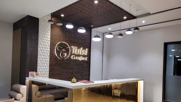 A reception desk with a modern design, featuring a logo and name on the wall behind it.