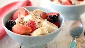 A bowl of fruit salad with various berries and a spoon.