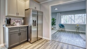 A modern kitchen with a stainless steel refrigerator, light-colored cabinets, and a herringbone-patterned backsplash. - Decatur Rocksteady Message for Summer Special (Decatur)