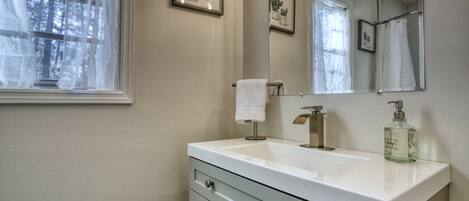 A bathroom with a white sink, a mirror, a towel rack, and framed pictures on the wall.