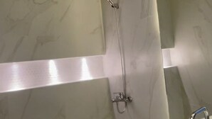 A modern bathroom with a marble sink, a shower with a handheld showerhead, and a large mirror. - Rateel Apartments 3 min walk from Badr Al Sama Hospital  (Salalah)