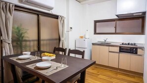Cocina compacta con comedor, equipada con refrigerador, estufa y lavamanos.
