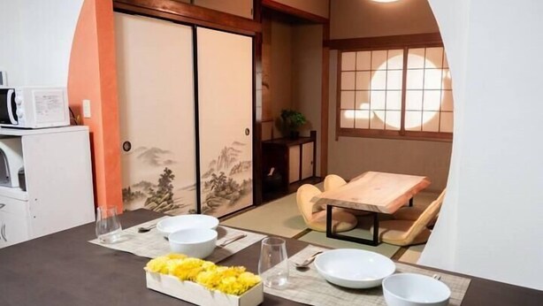 Una habitación japonesa tradicional con suelo de tatami, una mesa baja con cojín y una puerta corredera.
