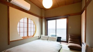 Habitación de hotel con cama, una silla, ventana con vistas y aire acondicionado.