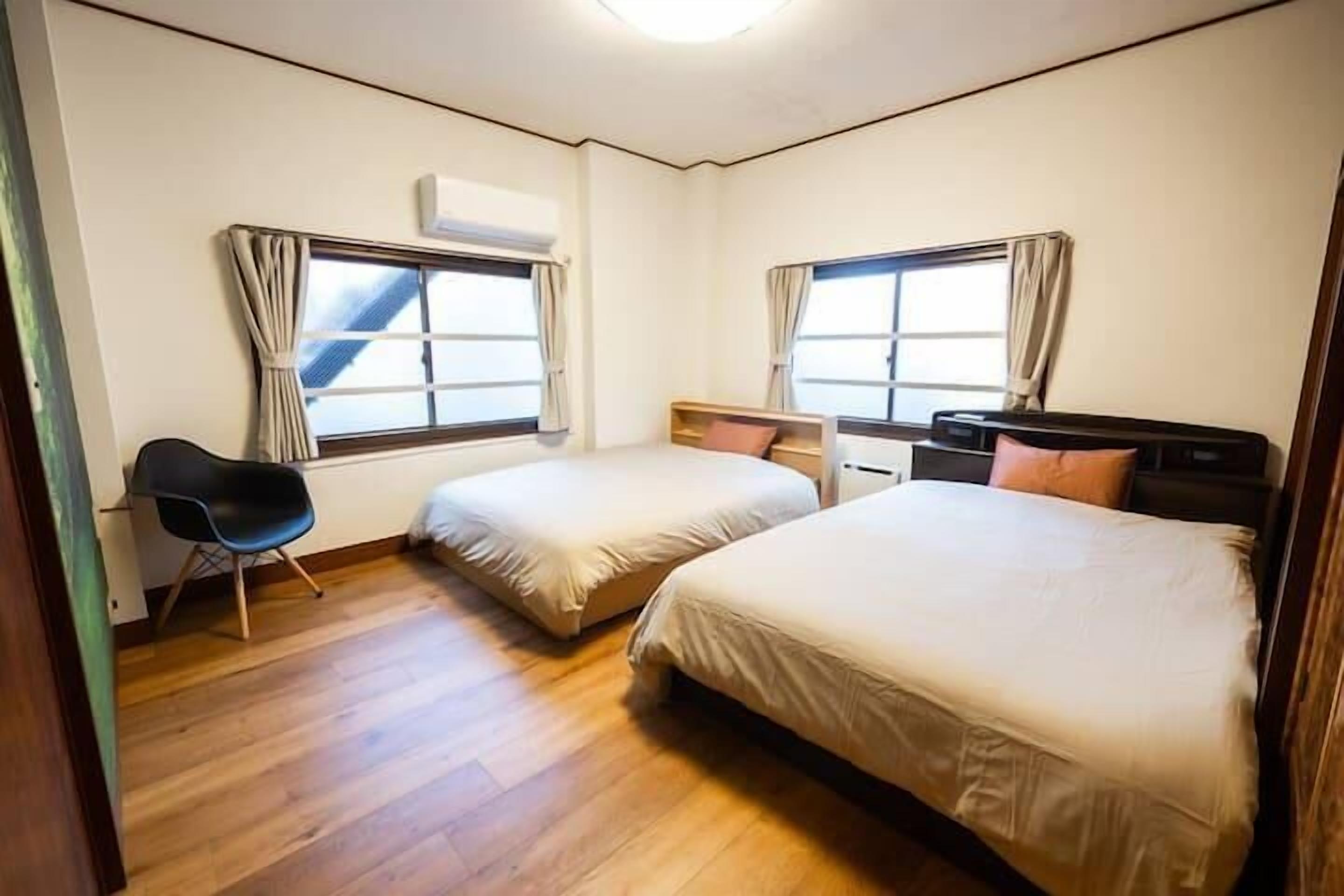 Une chambre avec deux lits, une chaise et un bureau.