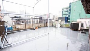 Una terraza en la azotea con barandilla de metal, antena parabólica y una vista despejada del paisaje urbano.