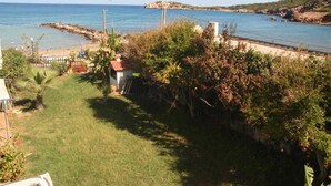 Una propiedad costera con jardín cubierto de césped, una casita y vista al mar.