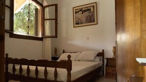 Un dormitorio con una cama de madera, una mesita de noche y un ventanal con vistas a árboles.
