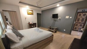 Habitación de hotel con una cama grande, un escritorio con silla, televisor en la pared y una puerta con el número 101.