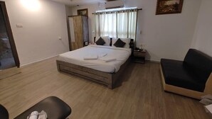 Un dormitorio con cama, mesita de noche, silla y un cuadro en la pared.