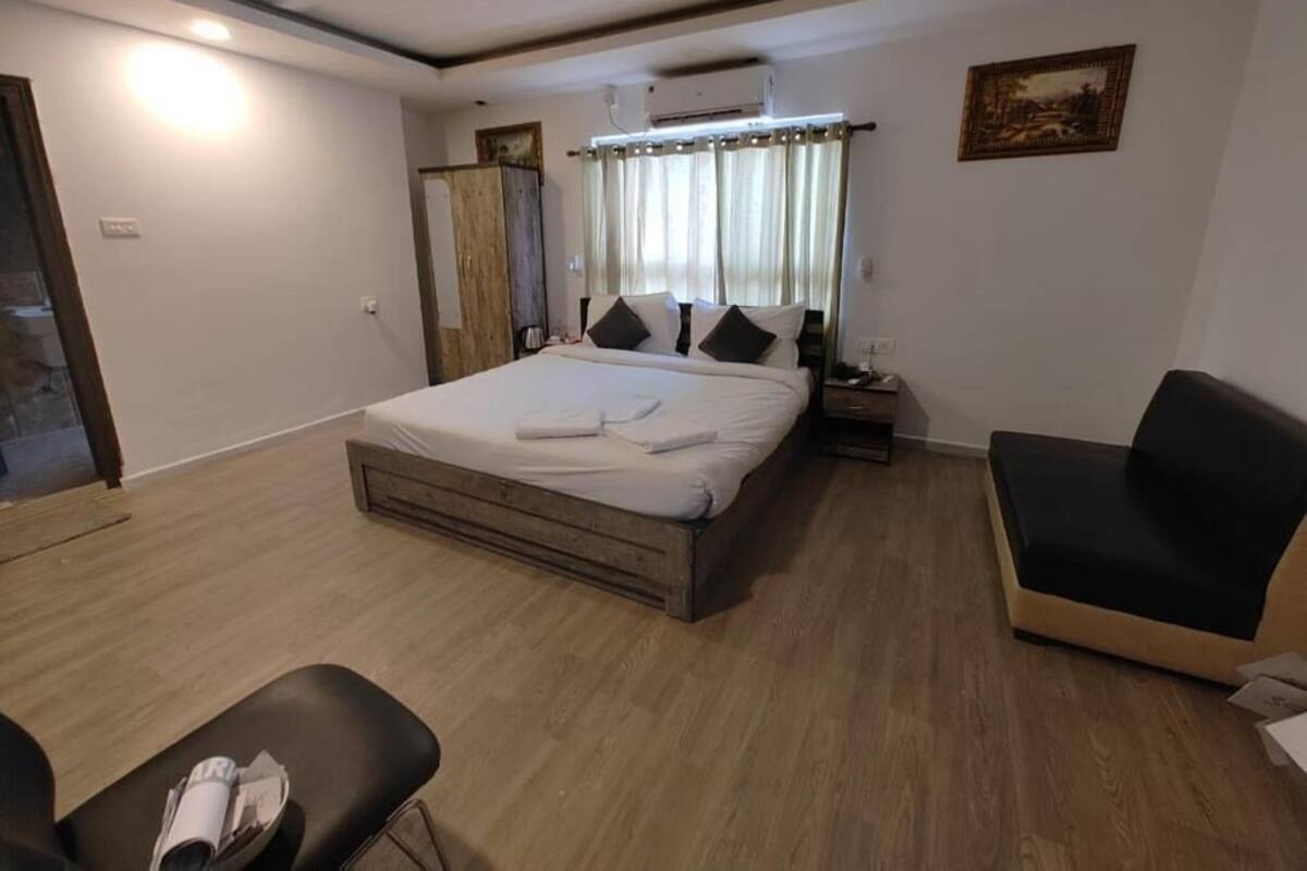 A bedroom with a bed, bedside table, chair, and a painting on the wall.