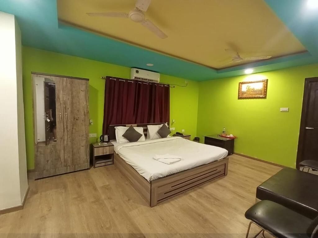A bedroom with a bed, a desk, a chair, a wardrobe, and a ceiling fan.