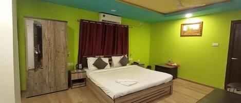 A bedroom with a bed, a desk, a chair, a wardrobe, and a ceiling fan.