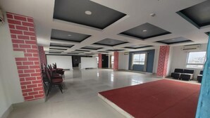 Una habitación amplia con alfombra roja, pared de ladrillo y techo con paneles blanco y negro.
