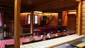 A cozy log cabin interior with a dining area featuring checkered tablecloths and wooden furniture. - Spacious 8-Bedroom Chalet (Barvaux)