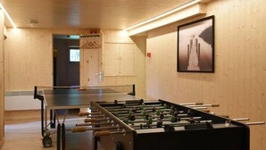 A room with a foosball table and a ping pong table, wooden walls, and a framed picture on the wall. - Spacious 8-Bedroom Chalet (Barvaux)