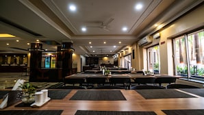 Un restaurant spacieux, doté de nombreuses tables et chaises, d’un réfrigérateur à boissons Coca-Cola et de grandes fenêtres offrant une vue sur l’extérieur.