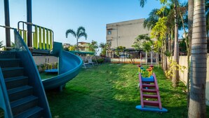 Une aire de jeux avec un toboggan, des balançoires et une structure d’escalade.