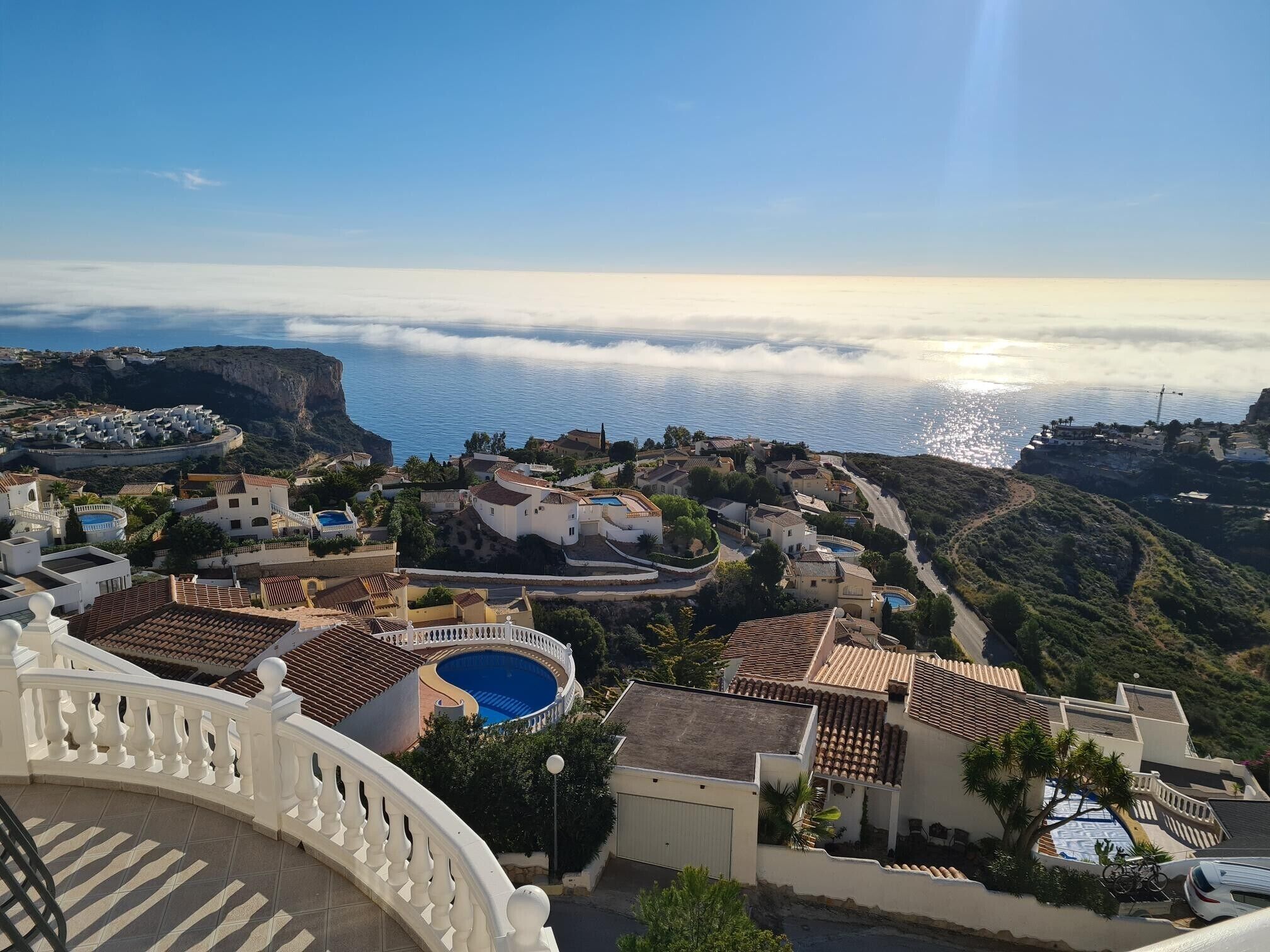 A coastal village with terraced houses, a swimming pool, and a view of the sea.