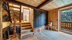 A wooden interior with a staircase, a door leading outside, and a view of the outdoors.