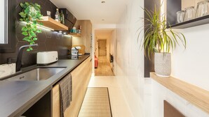 Eine moderne Küche mit integriertem Toaster, einer Spüle und einem Holzregal mit Küchenutensilien.