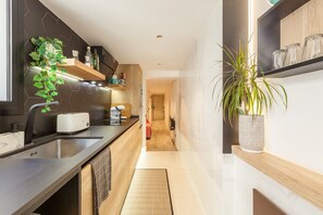 Een moderne keuken met een ingebouwde toaster, een spoelbak en een houten plank met keukengerei.