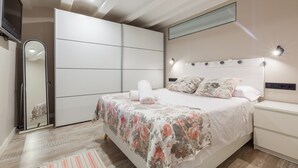 Ein Schlafzimmer mit einem Bett, einem Nachttisch, einem Kleiderschrank und einer Deckenleuchte.