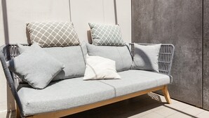 Ein graues Sofa mit gemusterten Kissen vor einer Betonwand.