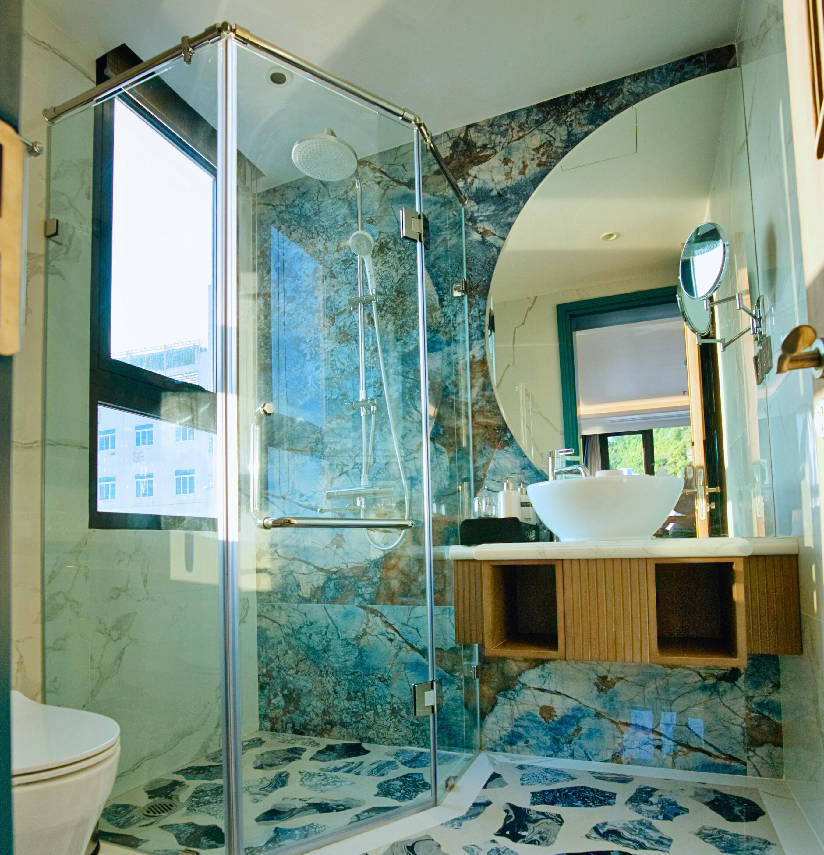 A modern bathroom with a glass-enclosed shower, a white sink, and a marble backsplash.