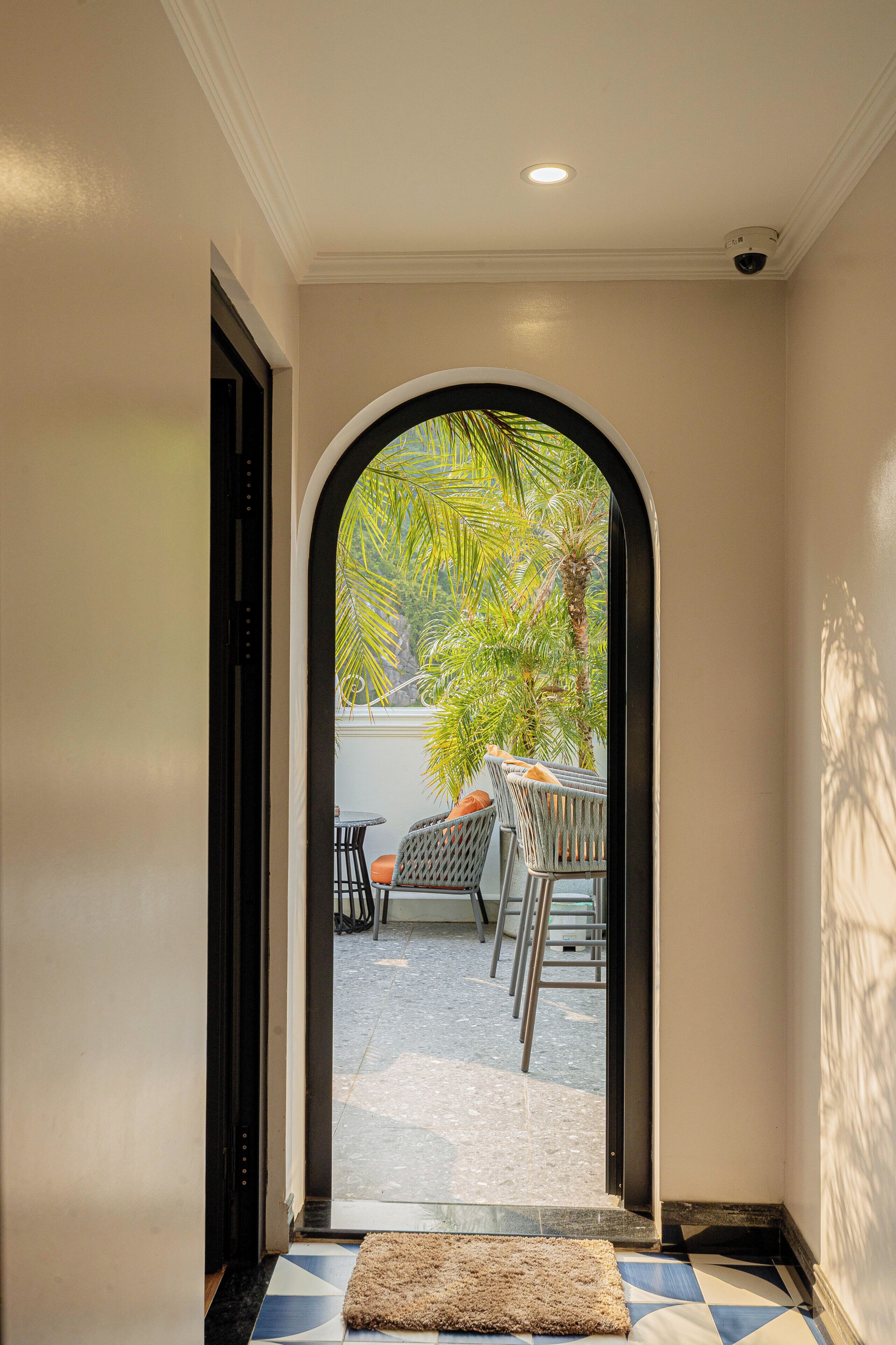 A hallway leading to an outdoor seating area with a view of palm trees.