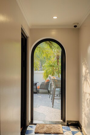 Un pasillo que conduce a un área de estar exterior con vistas a palmeras.