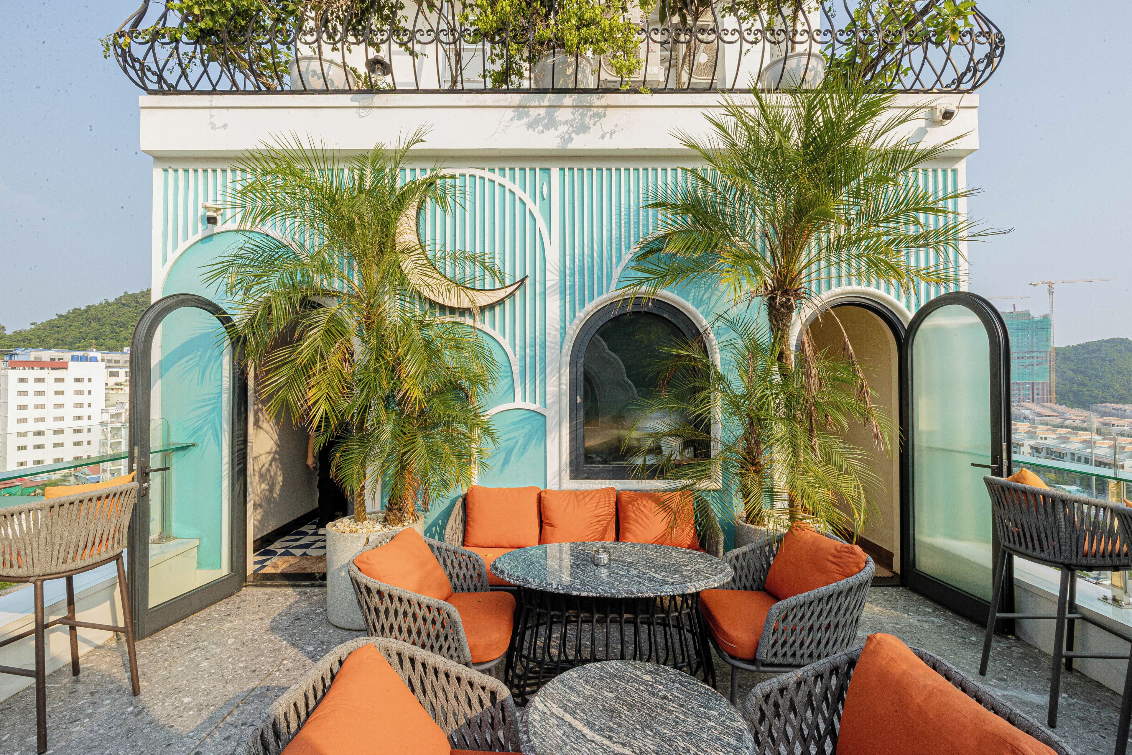 A rooftop terrace with outdoor seating, a view of the city, and a decorative building in the background.