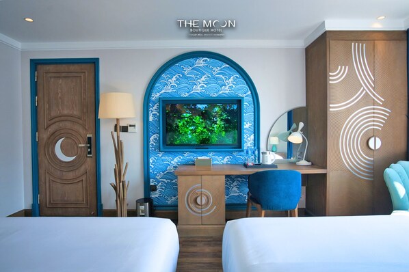 A hotel room with a TV, desk, two beds, and a decorative wall.