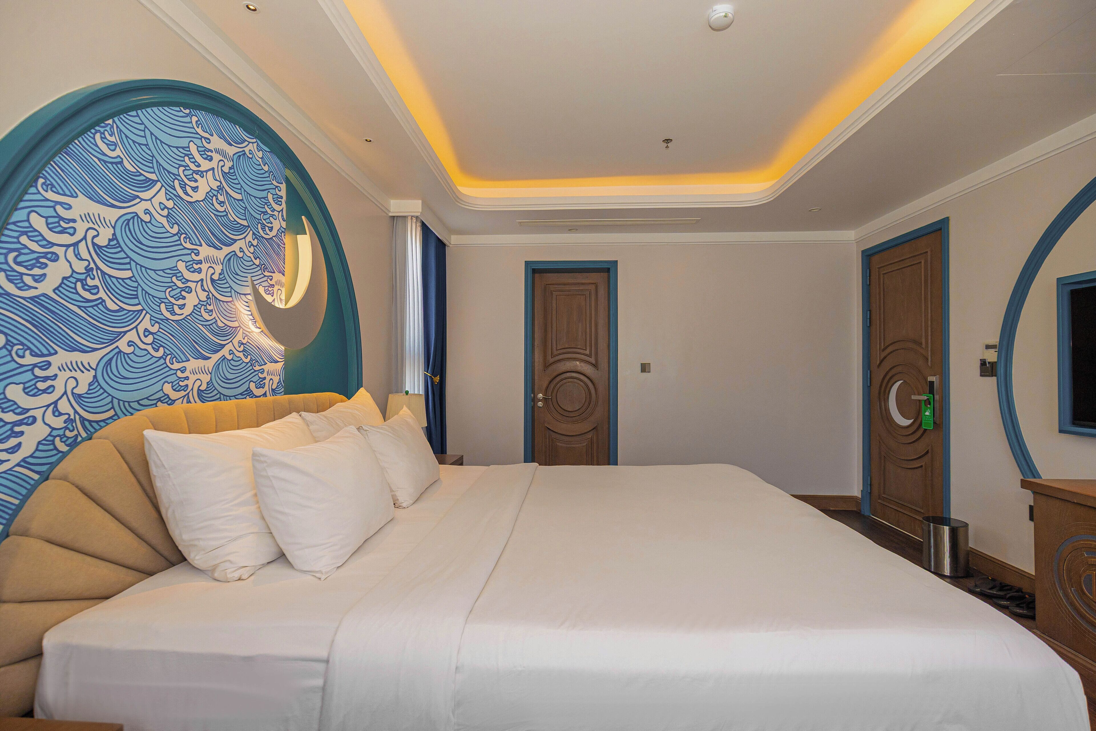 A hotel room with a large bed, a wall with a blue and white pattern, and a door with a circular design.