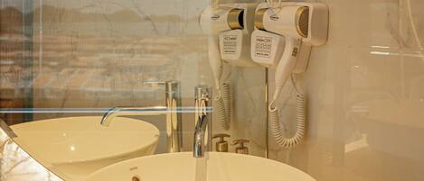 Une salle de bain avec deux lavabos, un miroir et un sèche-cheveux fixé au mur.