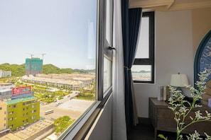 A hotel room with a view of a cityscape, including buildings and a construction site.