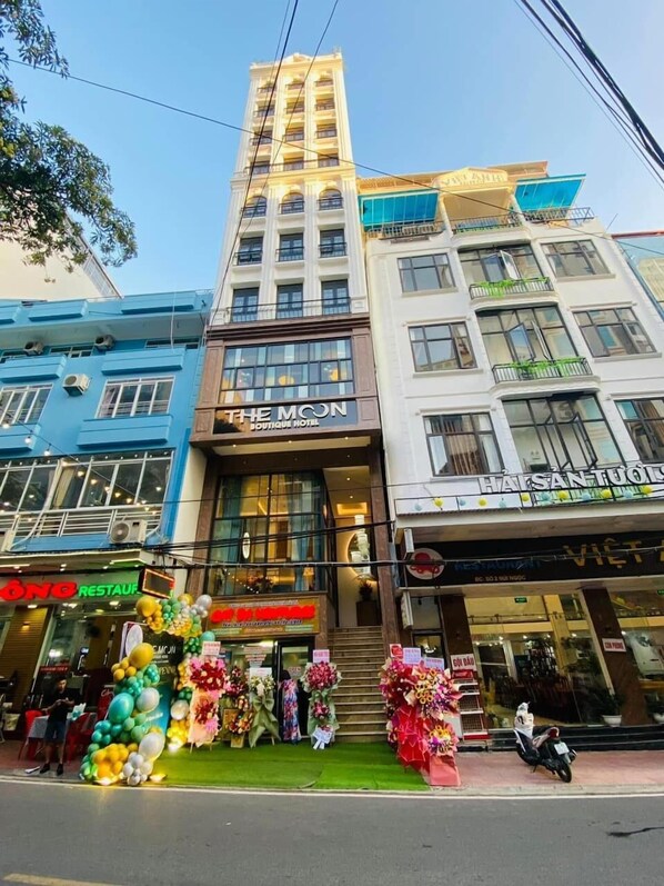 A hotel with a sign reading "The Moon Boutique Hotel" and a restaurant with a sign reading "HÀS SÁN TUOÏ". - The Moon Boutique Hotel Cat Ba (Hai Phong)
